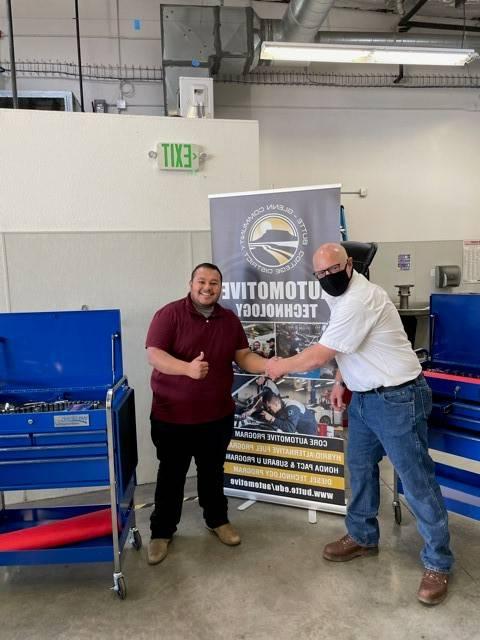 An automotive instructor shakes hands with student Damon Hughes.